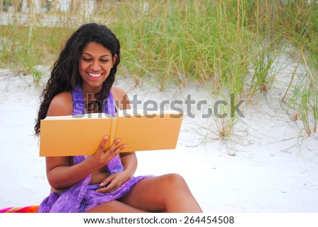 Beautiful young woman reading on the beach with blank book cover for Your Book Title