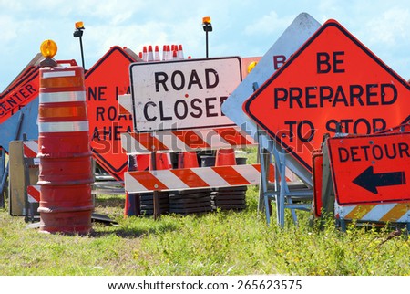 Colorful road signs stacked beside a road creating a wall of signs Colorful road signs stacked beside a road creating a wall of signs