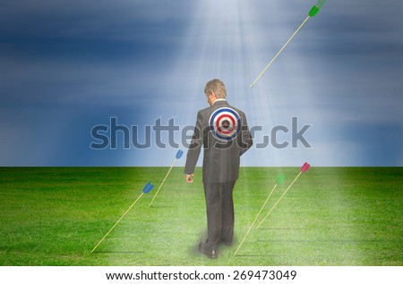 Target market concept showing a man with a target on his back with arrows all around him as a flying arrow is heading directly for him with dramatic background.