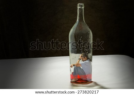 Addiction to alcohol depicted by a man trapped inside a bottle of booze
