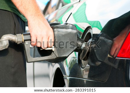 Closeup of a man pumping gas into his automobile.