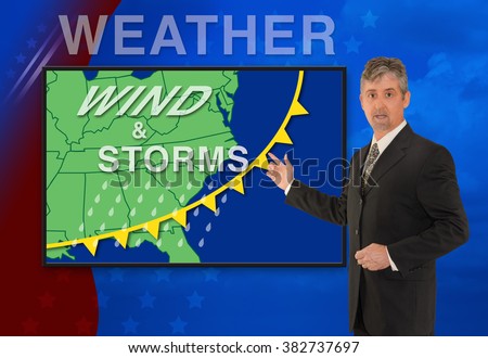 A tv television news weather meteorologist anchorman is reporting with a Wind & Storm graphic over a stormy black cloud photo on the monitor screen.