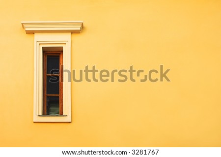 Window in a yellow wall of an old-fashioned Europe house.