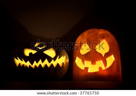 Two Jack-o\'-lanterns, Halloween pumpkin faces glowing in the night.