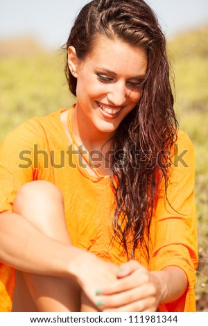 Portrait of young beautiful woman laughing wearing orange shirt