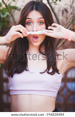 Funny face young woman with candy as mustache