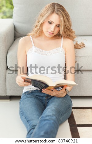 young beautiful woman reading a book on the floor