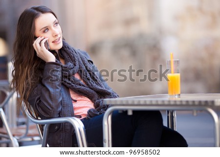 young beautiful woman drinking a orange juice while talking in a bar