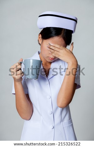 Young Asian nurse get  tired on gray background