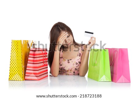 Beautiful Asian woman fed up with a credit card and shopping bags on table  isolated on white background