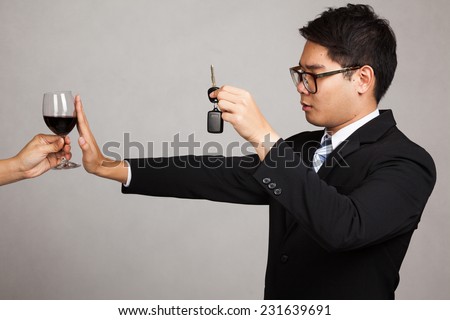 Asian businessman drive not drink , say no to wine with car key in hand on gray background