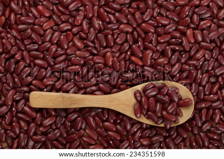 Top view of red kidney beans with wooden spoon with beans as background