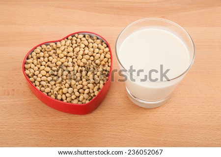 Soy milk in glass with soybeans in heart shape box on wood table