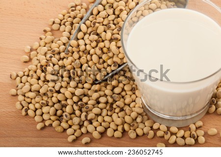 Soy milk in glass with soybeans and  transfer scoop on wood table