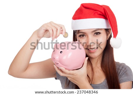 Asian girl with red santa hat put a coin to pink piggy bank  isolated on white background