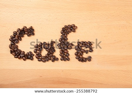 Roasted coffee beans in cafe word shape on wooden background