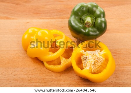 Cut yellow and green bell peppers on wooden cutting board