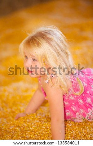 Pretty Young Child Playing in fall harvest Corn Pile.