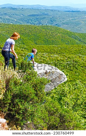 Mother and son watching from the cliff of the valley (Greece)