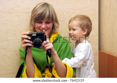 Happy family (mother with small boy) examine photos on compact camera
