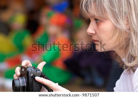 Mother making photos using compact camera on children\'s theatrical performance