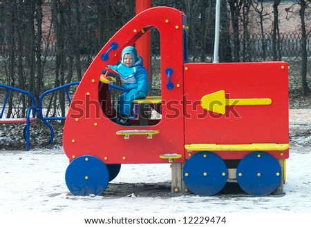 Little boy is learning to drive on the winter pleasure-ground in park.
