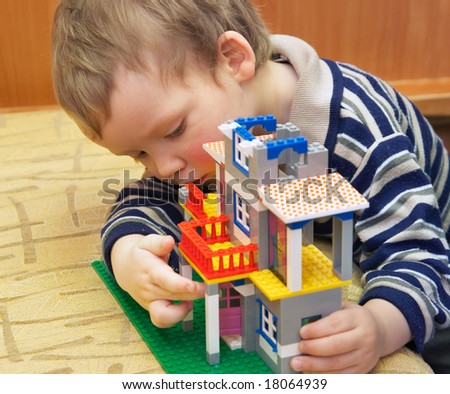 Small boy play with building set for children (built a house)