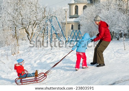 Happy family (mother with small boy and girl) on winter snow covered courtyard