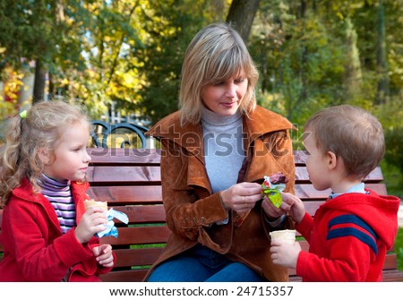 Happy family (mother with children) eat  ice cream in autumn city park