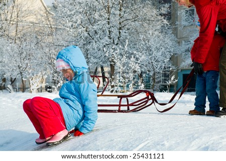 Happy family (mother with small boy) in winter snow covered courtyard near house