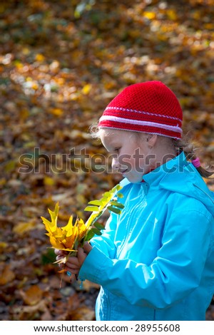 Happy small girl with oak leafs in golden autumn city park