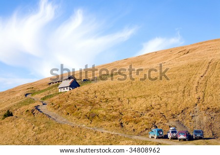 Carpathian Mountains (Ukraine) autumn landscape with cattle-breeding farm and country road with some 4WD cars.