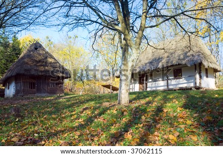 Ukrainian historical country wooden hut with thatched roof and autumn garden grass near