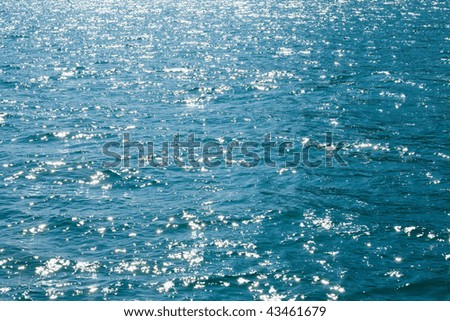 Azure sea water surface with ripple and sun reflection sparkles