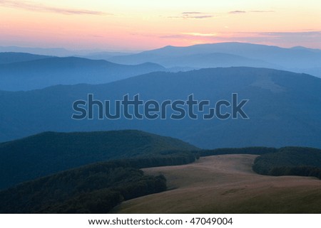 Autumn sunrise mountain view with haze, forest and sun on sky (Carpathian, Ukraine)