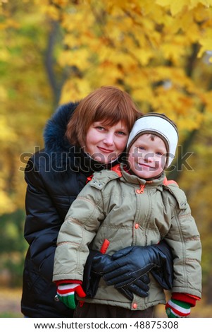 Mother with small son in golden autumn city park