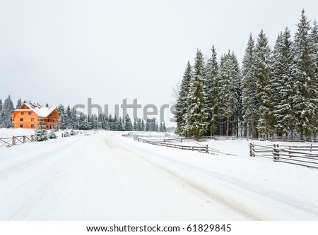 winter dull mountain landscape with  fence , wooden house and country road