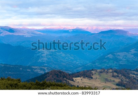 Autumn evening plateau landscape with lust golden-pink sunlight on mountains and evening glow in sky