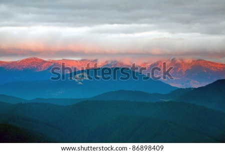 Autumn evening landscape with lust golden-pink sunlight on mountains and evening glow in sky