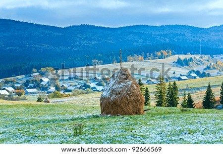 First winter snow on October Carpathian mountain plateau with village and highway far away