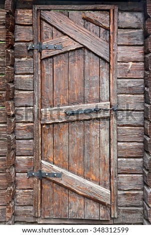 Stylized antique wooden door with wrought-iron hinges and hook