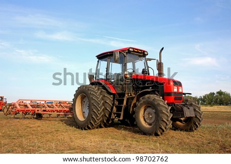 Color photo of a red tractor with a harrow