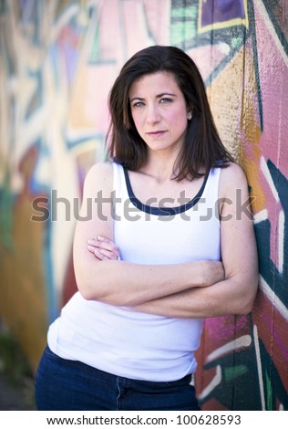 beautiful woman in front of a graffiti covered wall