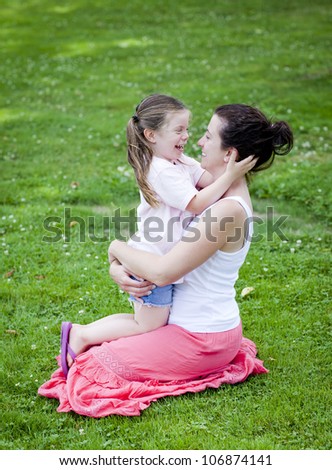 Pretty mother and daughter outside hugging portrait