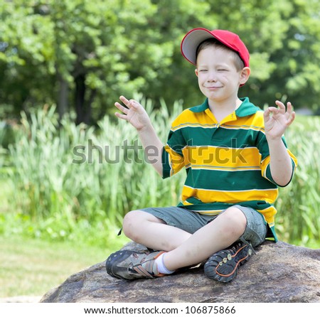 Cute boy with big smile meditating outdoors portrait