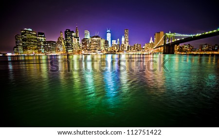 Lower Manhattan and Brooklyn Bridge in New York City at night with reflection in water