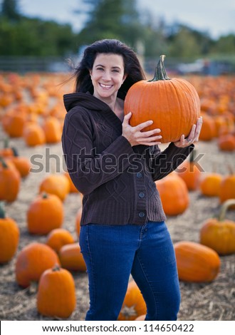 Woman at pumpkin patch selecting a pumpkin