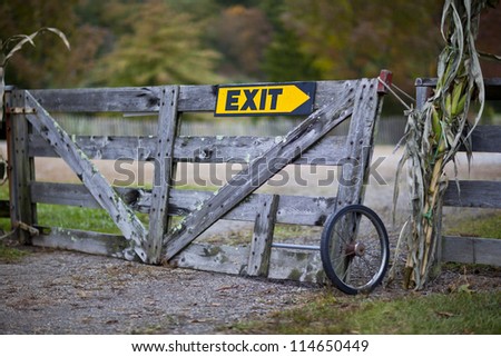 Old wooden gate on farm with exit direction sign
