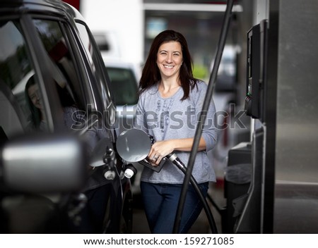 Pretty woman filling her car with petrol at gas statiion
