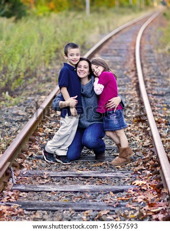 Beautiful mother and her children on train tracks